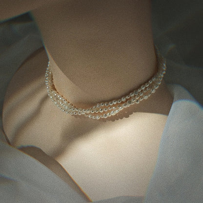 a female model wearing triple strand pearl necklace