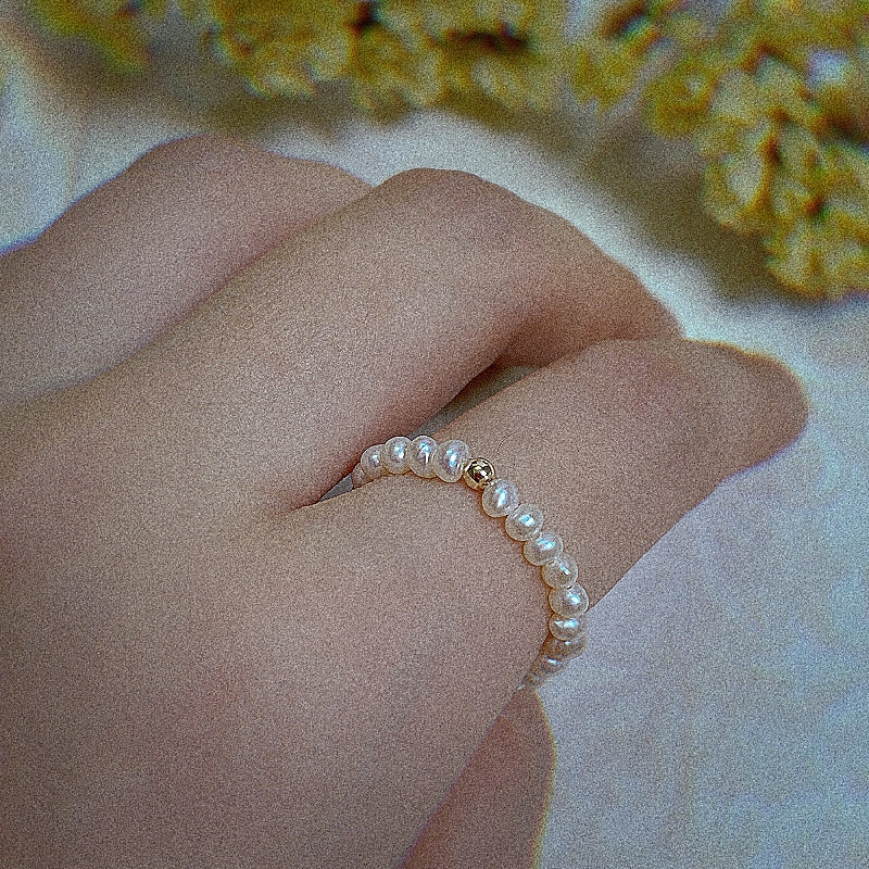 Female model wearing baroque seed pearl ring with golden bead molly with filter