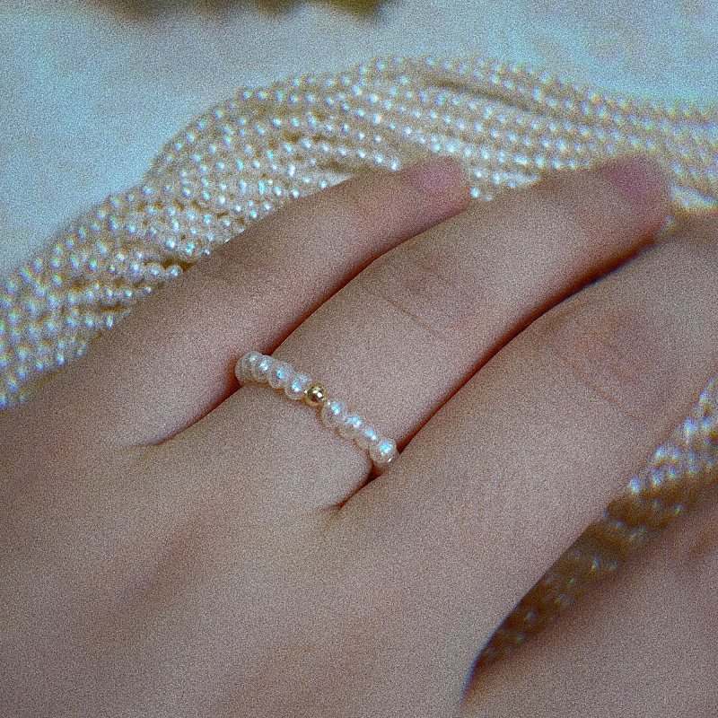 Female model wearing baroque seed pearl ring with golden bead molly