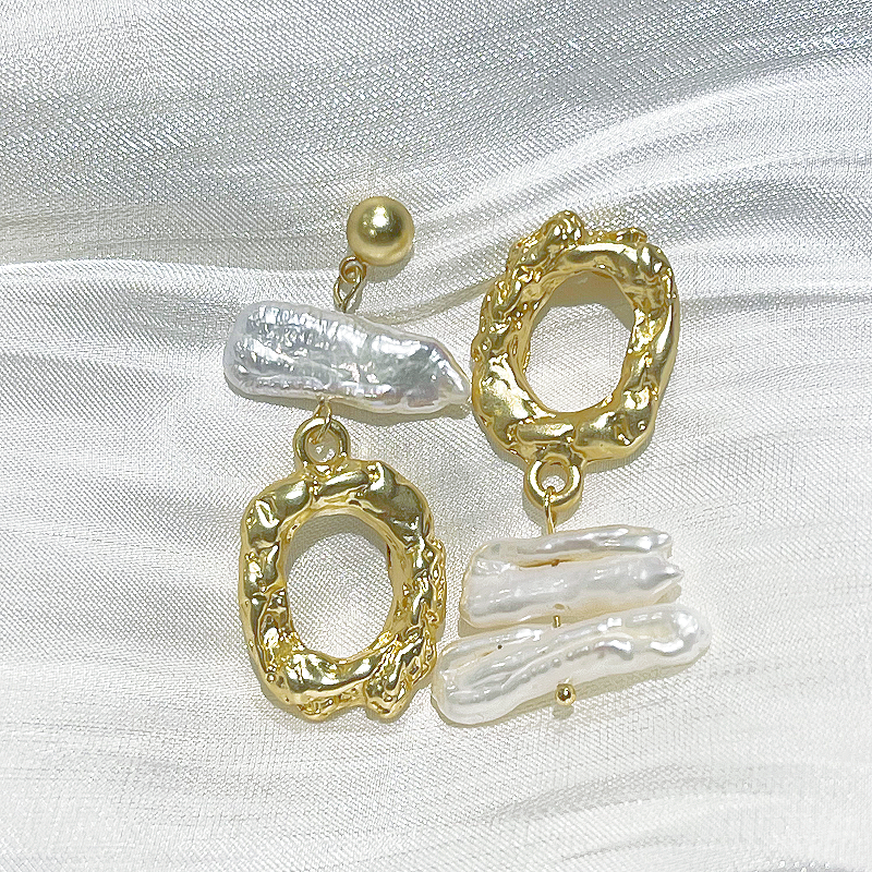 Free-form Style Baroque Freshwater Pearl Earrings Florence in gold lying on white fabric studio image