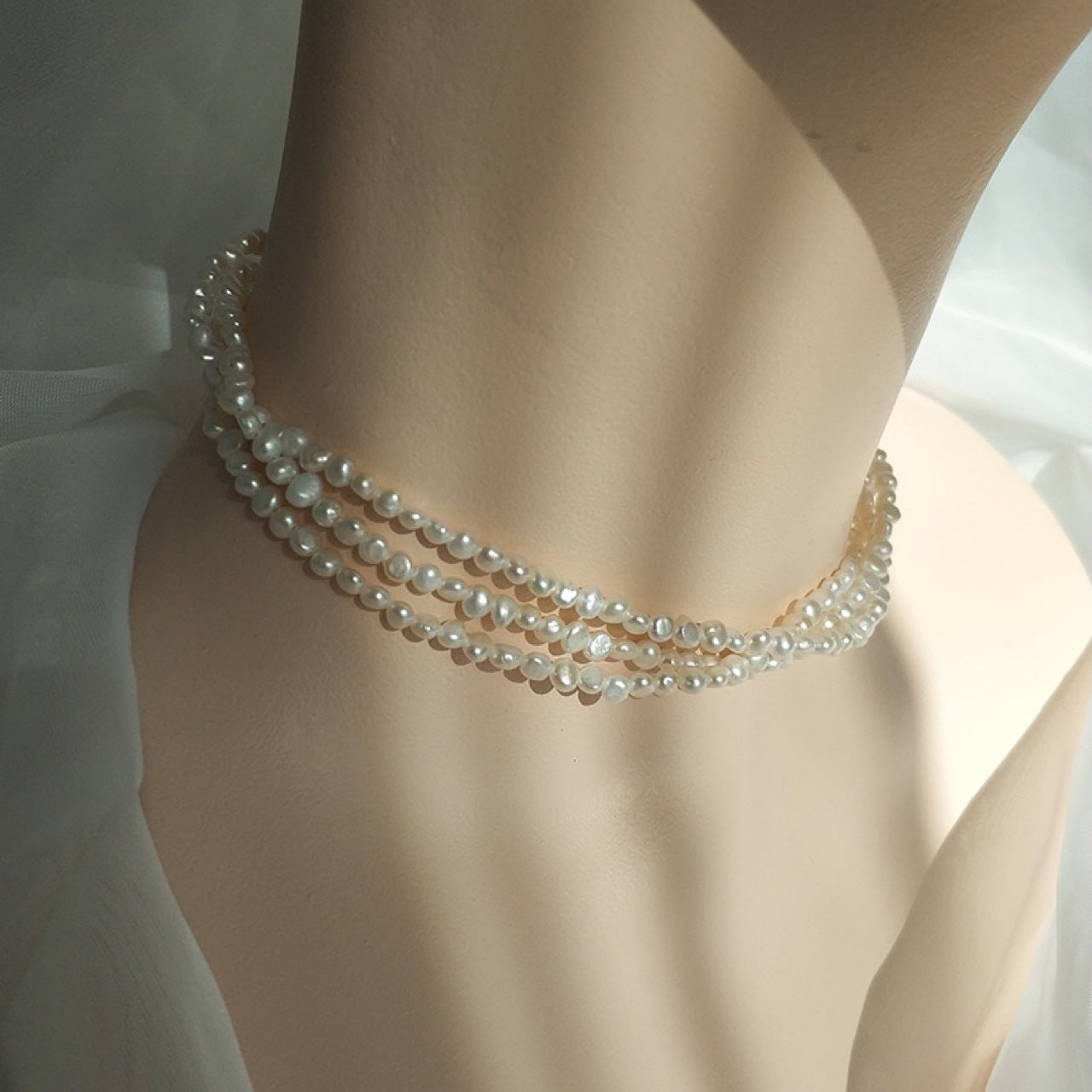 A female model wearing triple strand pearl necklace studio image