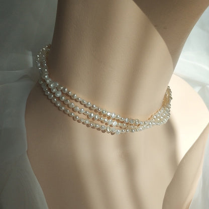A female model wearing triple strand pearl necklace studio image
