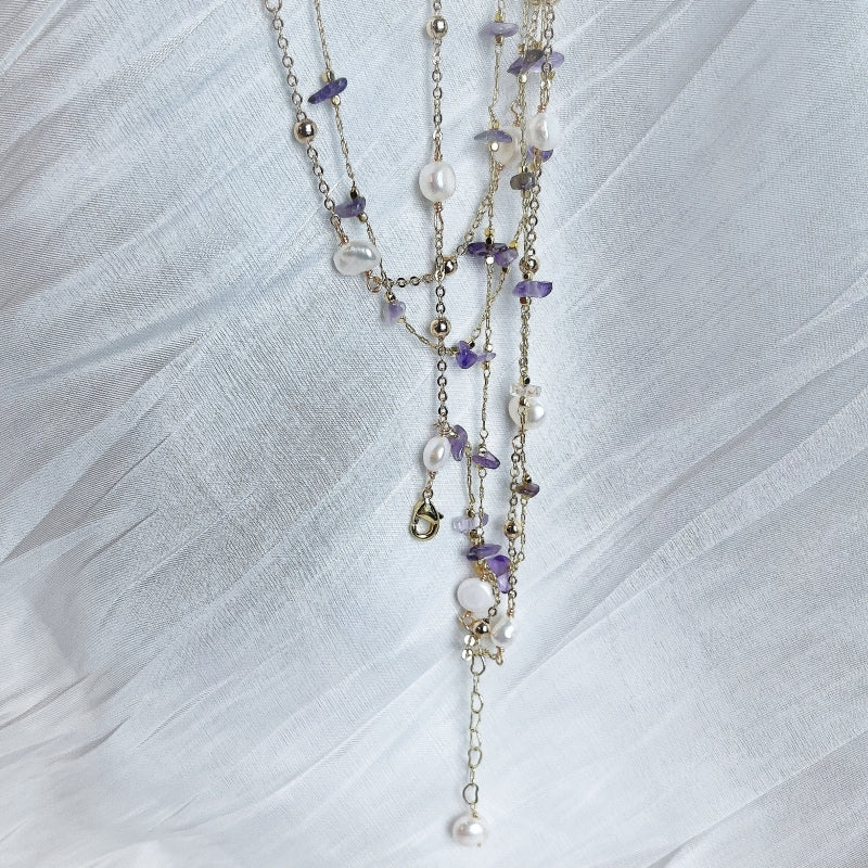 Natural Amethyst and Freshwater Pearl Double Layered Necklace Doris lying on white satin fabric